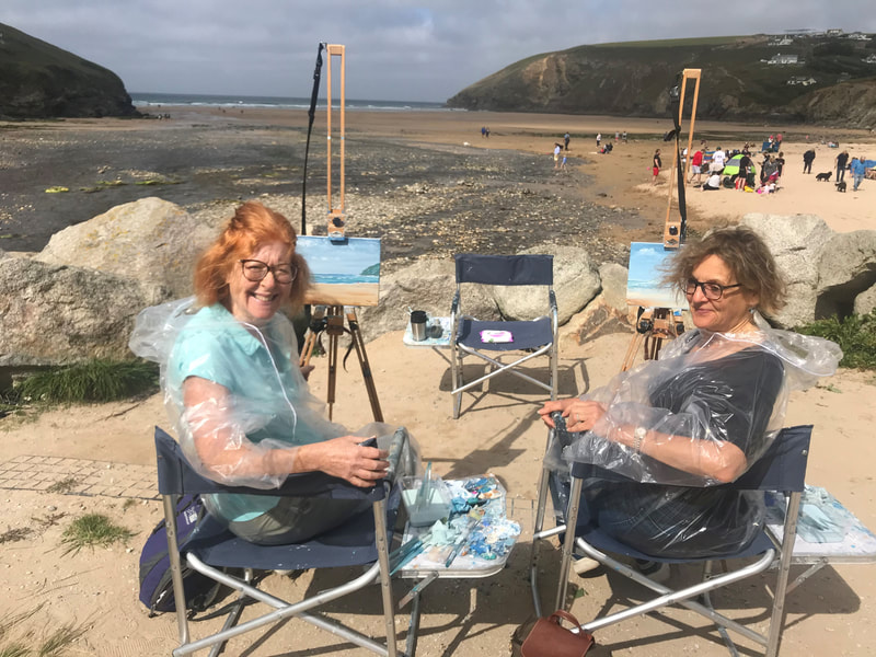 A pair of ladies completing their paintings on easels after a lesson with jeanni at Mawgan Porth
