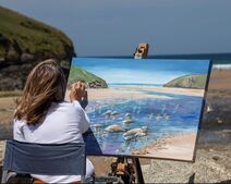 Picture of jeanni painting on beautiful Mawgan Porth Beach in Cornwall. Jeanni teaches art at the beach and across the world.