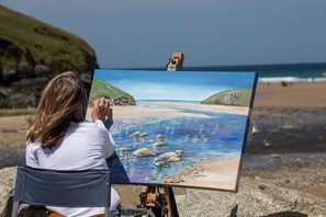 Picture of jeanni painting on beautiful Mawgan Porth Beach in Cornwall. Jeanni teaches art at the beach and across the world.
